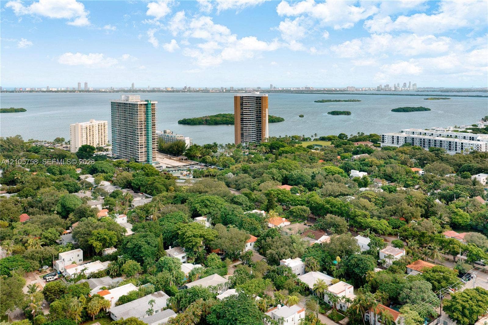 668 NE 70th Street, Miami, FL 33138 Aerial perspective of a coastal residential community featuring dense mature tree canopy, proximity to open water, and distant skyline