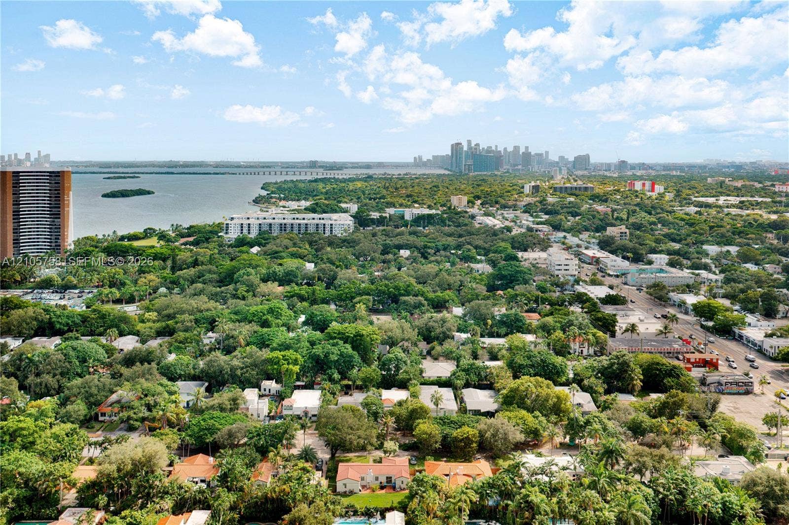 668 NE 70th Street, Miami, FL 33138 Aerial perspective featuring coastal surroundings, prominent urban skyline, expansive tree canopy, and proximity to open water