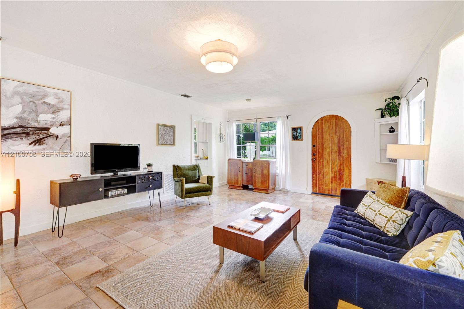 668 NE 70th Street, Miami, FL 33138 Living area featuring natural stone tile flooring, an arched wood entry door, and built-in shelving