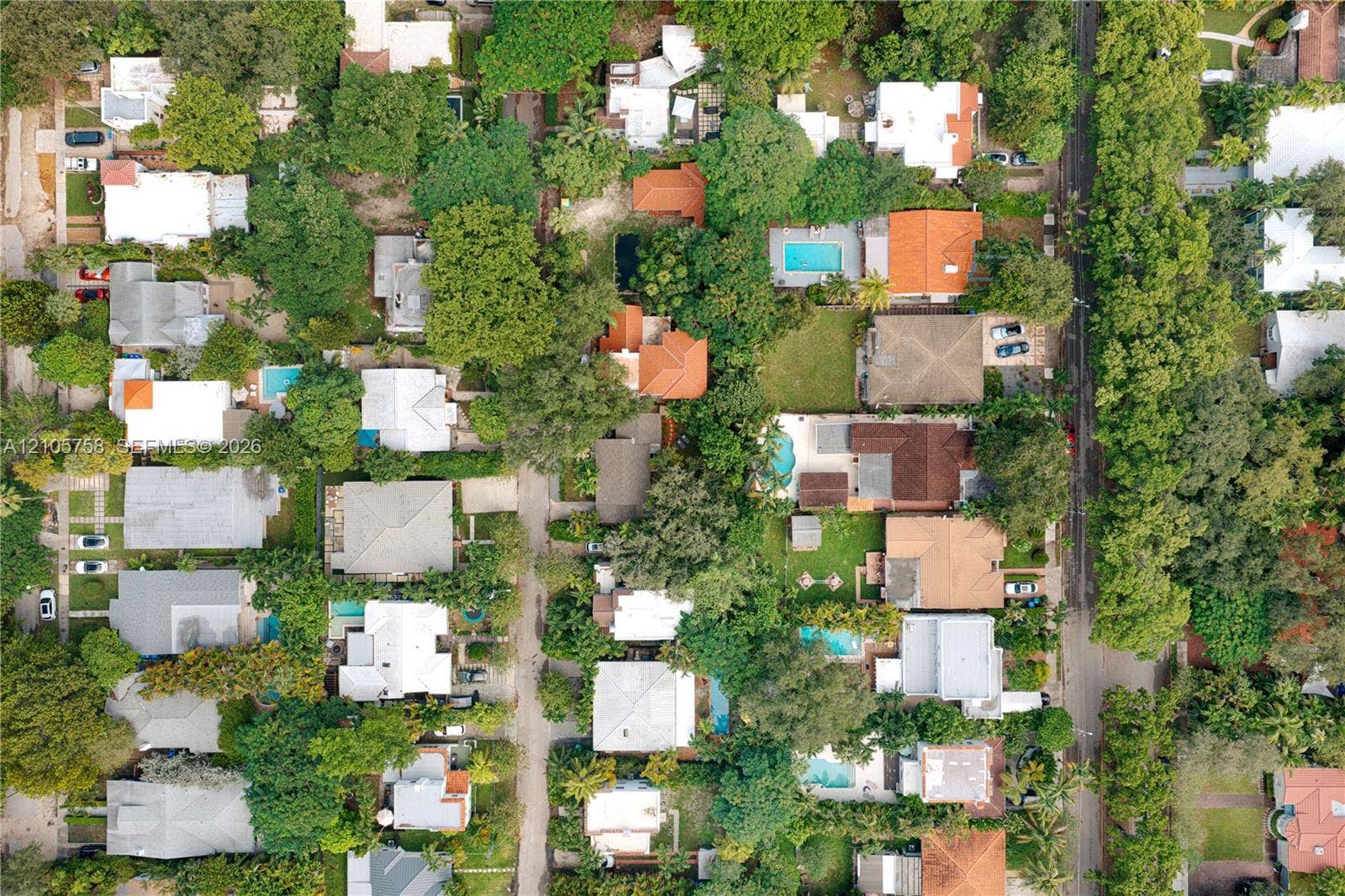 668 NE 70th Street, Miami, FL 33138 Aerial perspective of a neighborhood featuring dense tree canopy, established residential lots, varied roof pitches, and multiple private swimming pools
