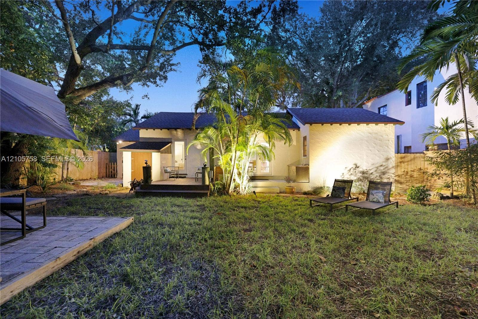 668 NE 70th Street, Miami, FL 33138 Backyard featuring mature trees, a multi-level wood deck, paver hardscaping, and privacy fencing
