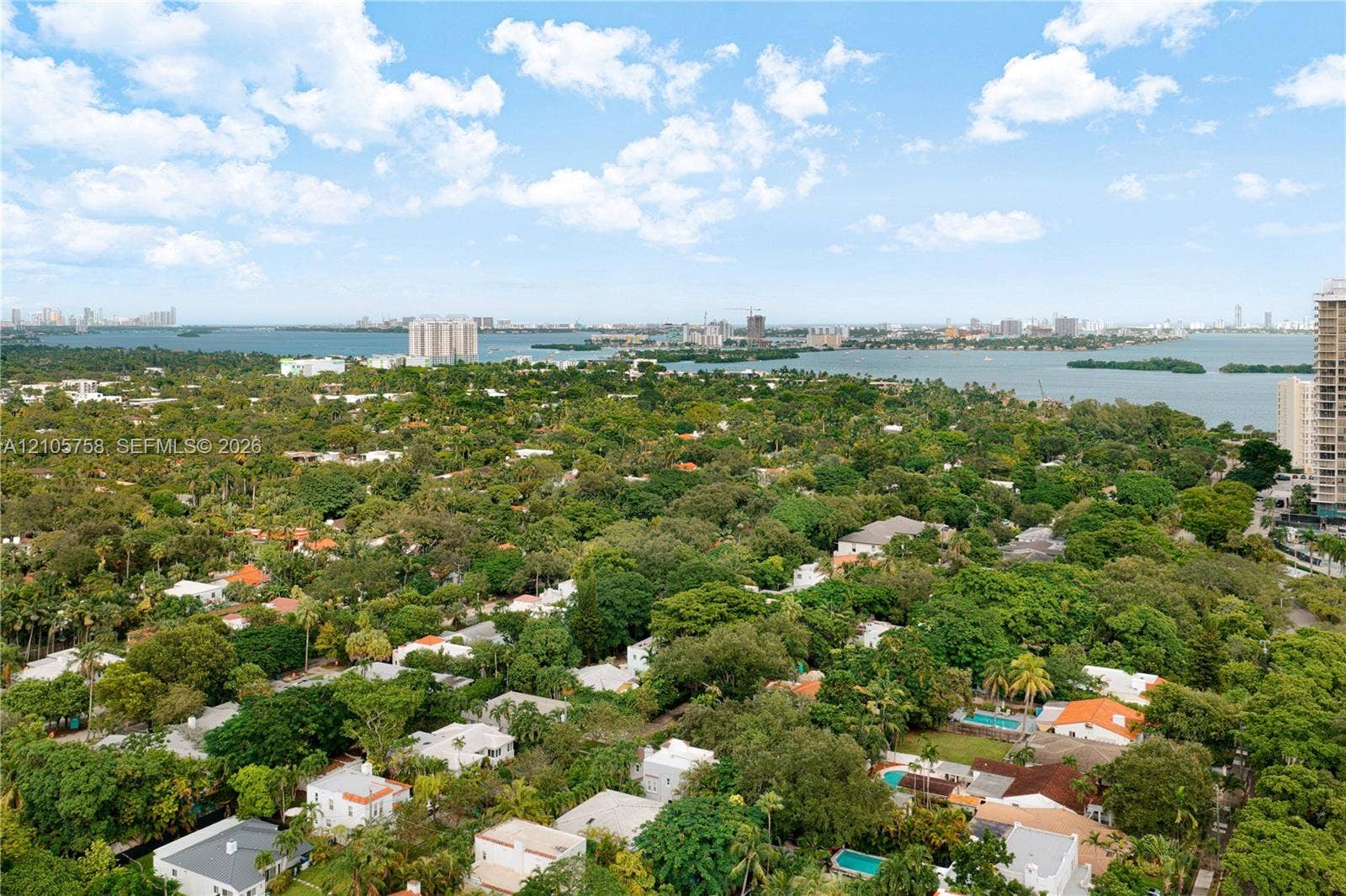 668 NE 70th Street, Miami, FL 33138 Aerial perspective featuring expansive tree canopy, coastal waterway, and urban skyline
