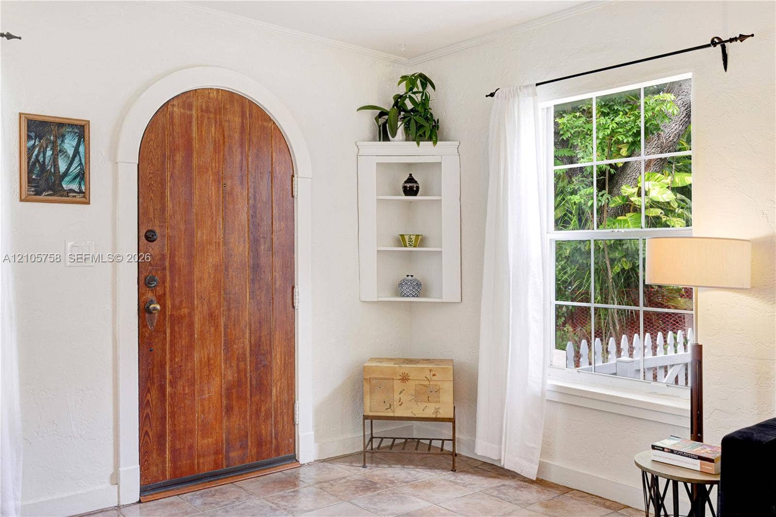 668 NE 70th Street, Miami, FL 33138 Arched wooden entrance door with metallic hardware, multi-pane window, and built-in corner shelving unit