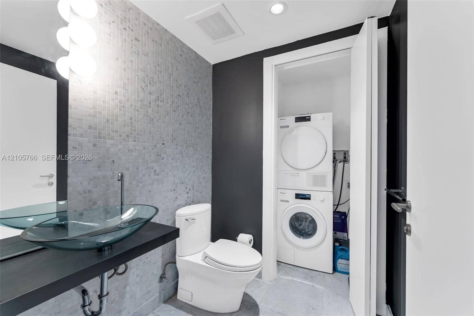 200 Biscayne Boulevard Way, #4408, Miami, FL 33131 Half bath with glass vessel sink, mosaic tile and the stacked Miele washer and dryer.