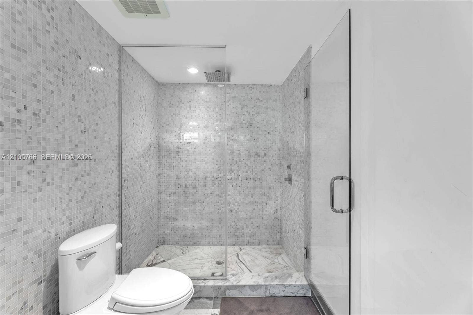 200 Biscayne Boulevard Way, #4408, Miami, FL 33131 Primary bath with a glass-enclosed walk-in shower, rain shower head and mosaic tile walls.