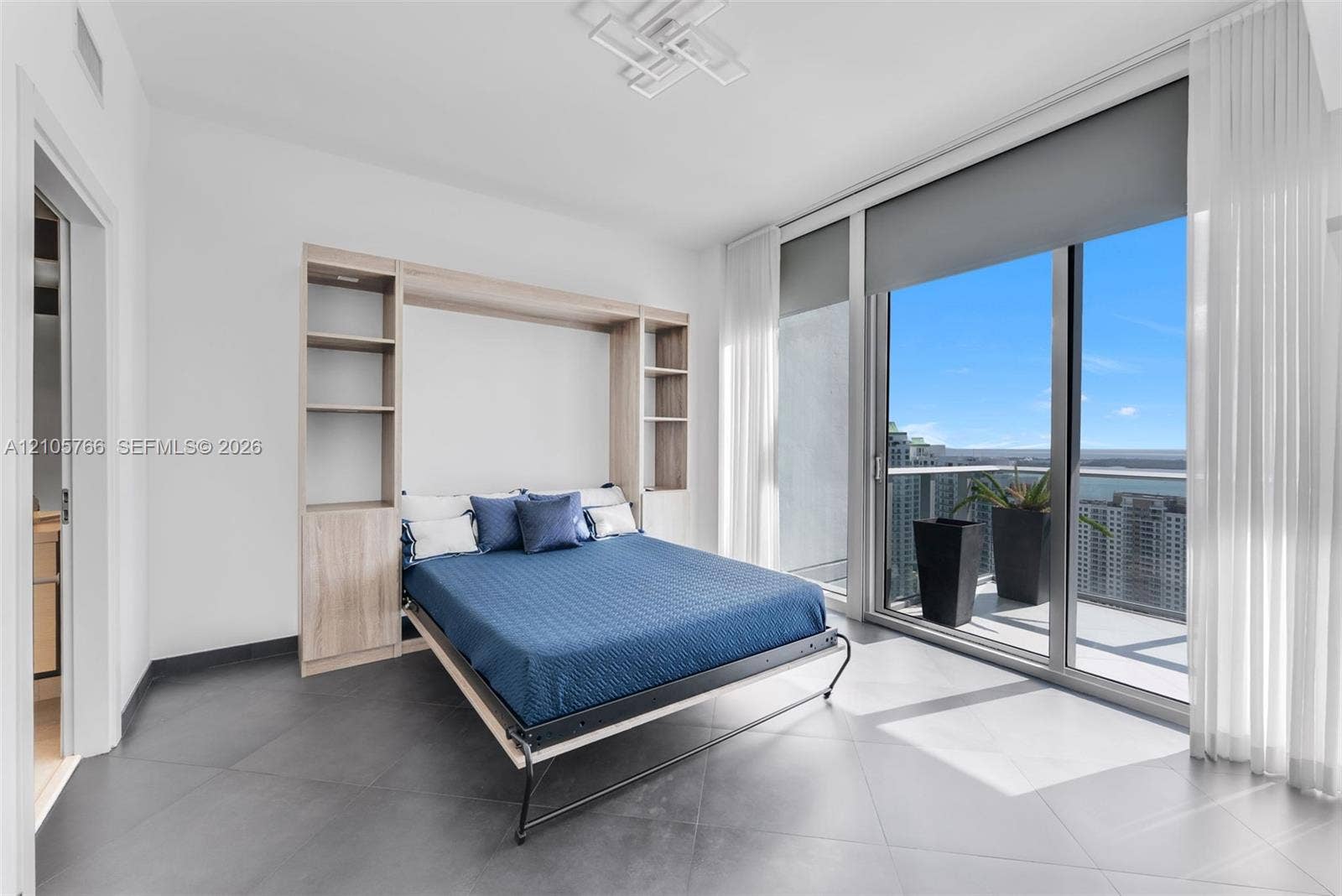 200 Biscayne Boulevard Way, #4408, Miami, FL 33131 Secondary bedroom with Murphy bed, built-in shelving and sliding doors to the terrace.