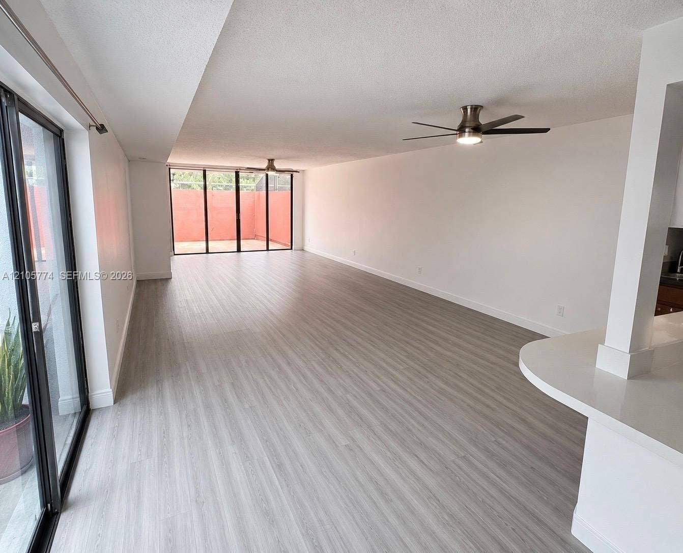 10343 Greenhouse Road, Pembroke Pines, FL 33026 Open floor plan featuring wood-finish flooring, two ceiling fans, floor-to-ceiling glass sliding doors, and a quartz countertop peninsula