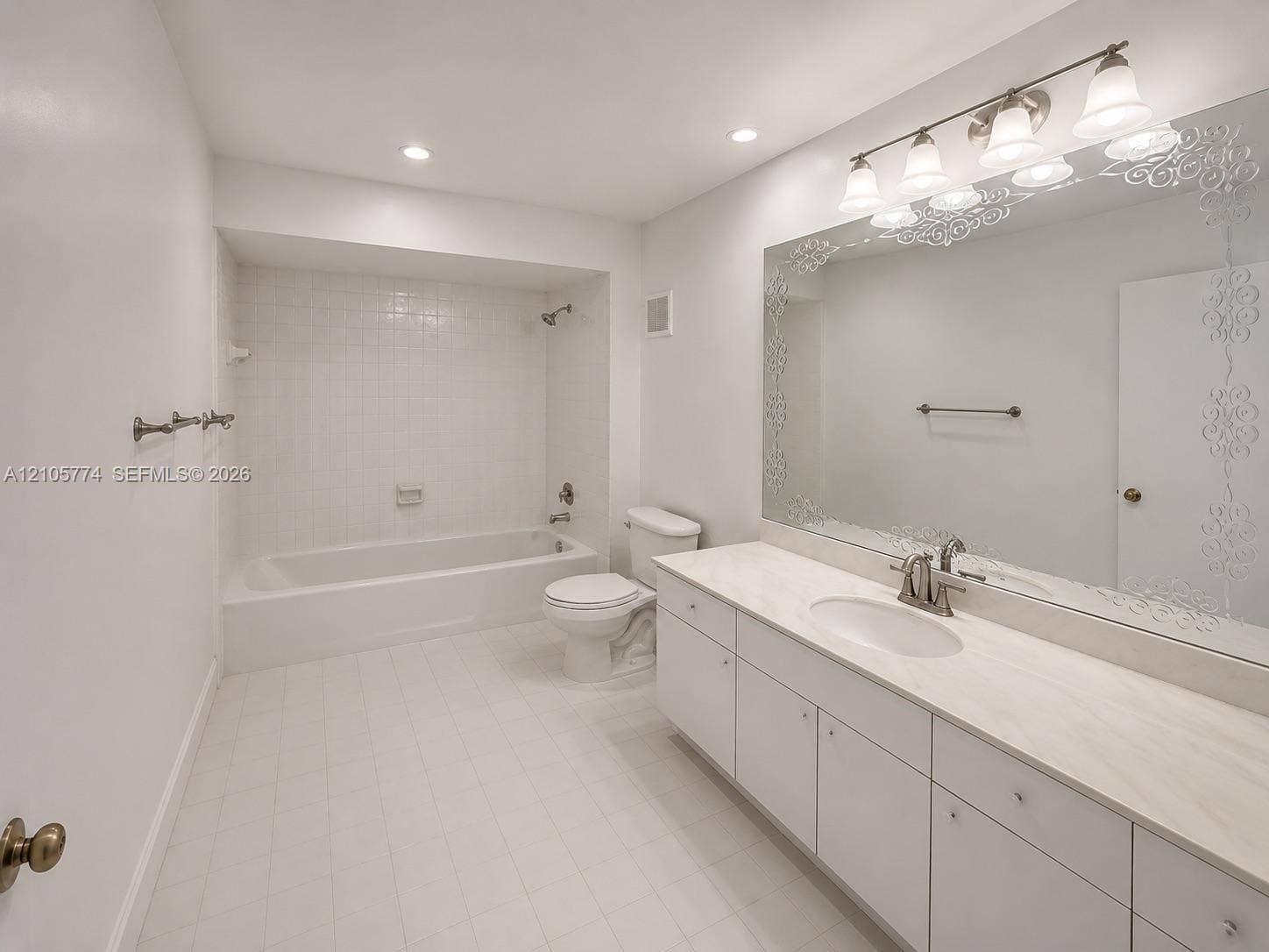 10343 Greenhouse Road, Pembroke Pines, FL 33026 Full bathroom featuring a white vanity with a stone countertop, an inset sink, an oversized decorative-edge wall mirror, and a tiled tub-shower combination