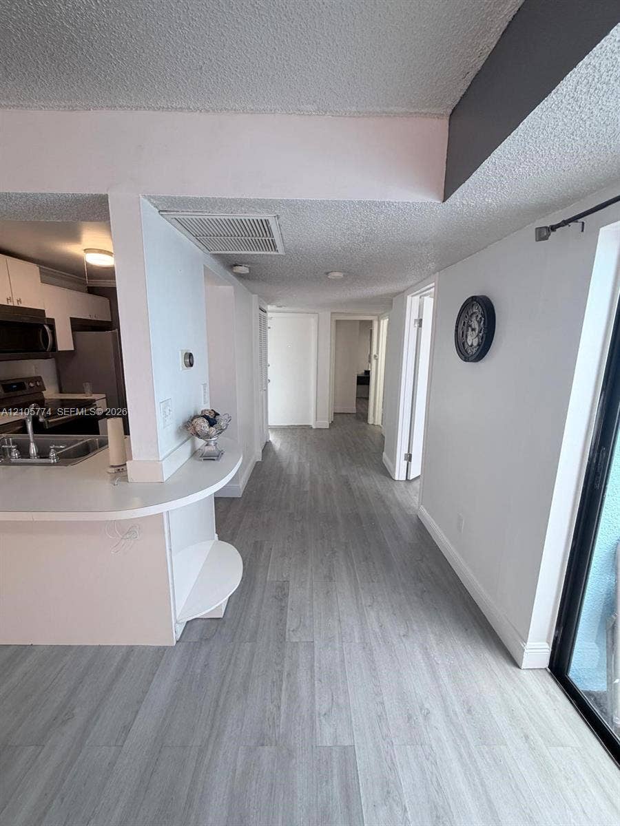 10343 Greenhouse Road, Pembroke Pines, FL 33026 Kitchen featuring white cabinetry, wood-finish flooring, and a curved peninsula countertop