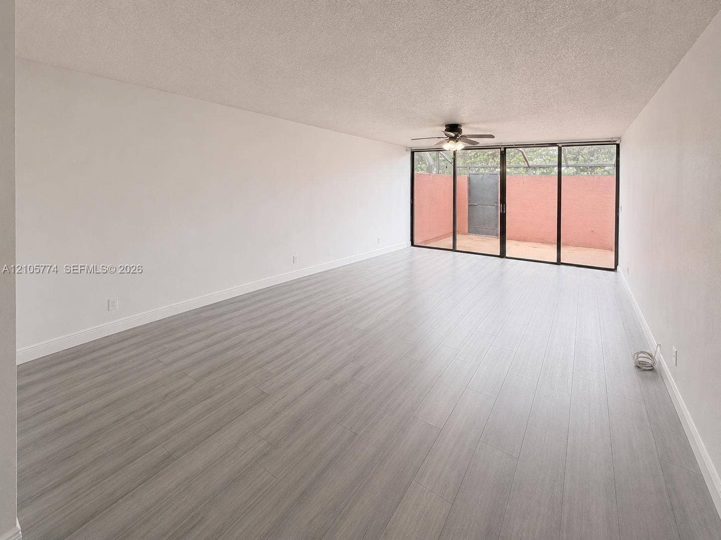 10343 Greenhouse Road, Pembroke Pines, FL 33026 Interior space featuring wood-finish flooring, a ceiling fan with integrated lighting, and floor-to-ceiling sliding glass doors leading to an exterior patio