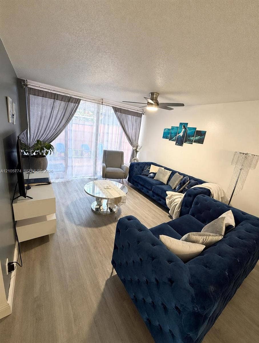 10343 Greenhouse Road, Pembroke Pines, FL 33026 Living space featuring light wood-finish flooring, a ceiling fan with integrated lighting, and sliding glass doors with an accent wall