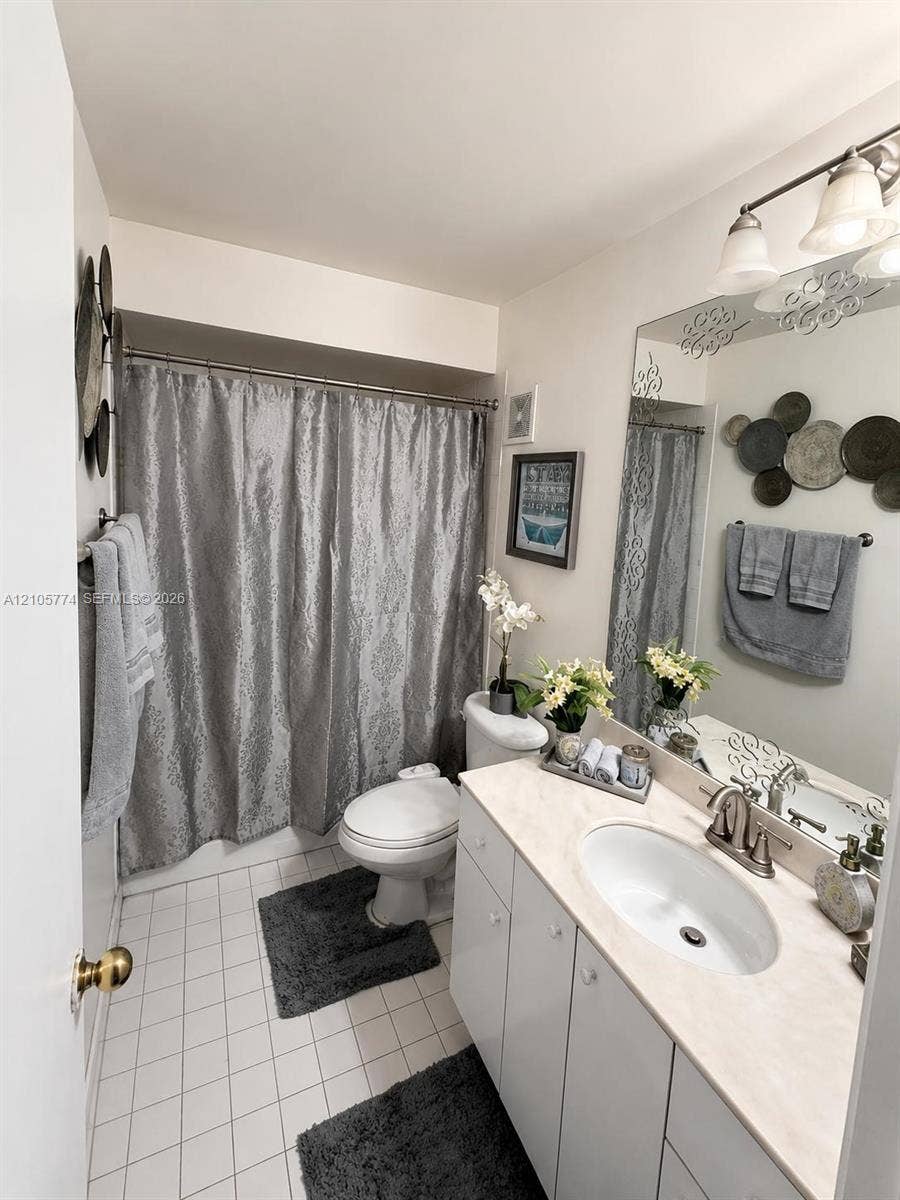 10343 Greenhouse Road, Pembroke Pines, FL 33026 Bathroom featuring a vanity with an integrated oval basin and solid-surface countertop, a multi-bulb vanity light fixture, a large wall-mounted mirror, and tile flooring