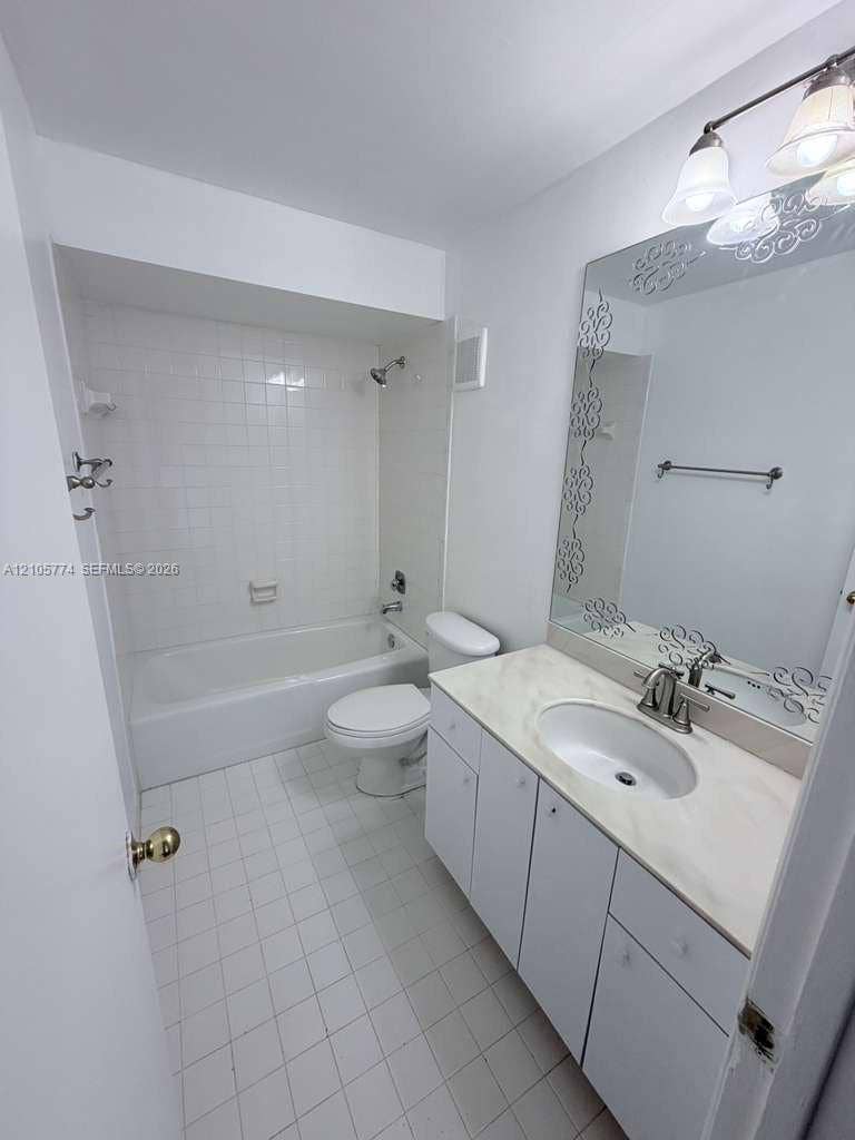 10343 Greenhouse Road, Pembroke Pines, FL 33026 Bathroom featuring a vanity with an integrated countertop, oval sink, decorative mirror, three-light fixture, and a tiled shower-tub combination