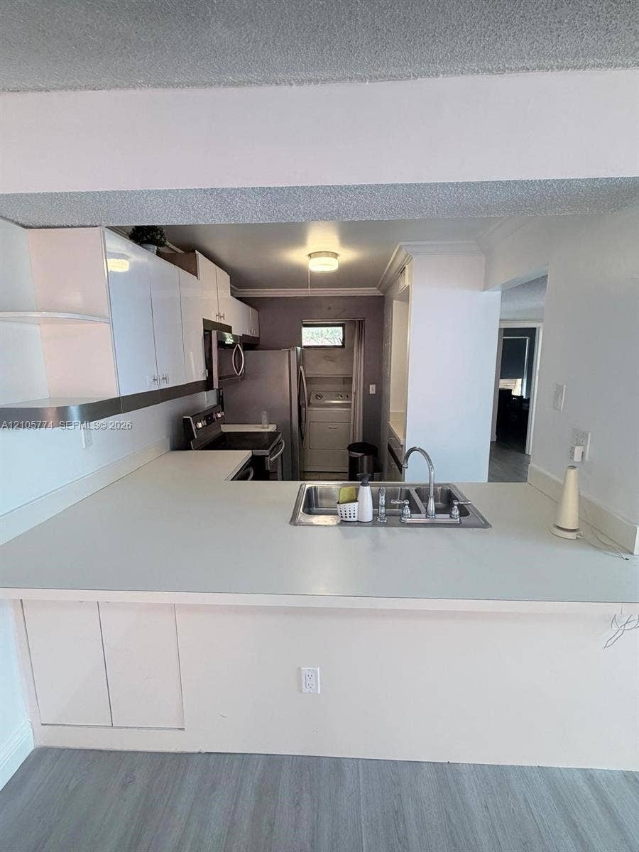 10343 Greenhouse Road, Pembroke Pines, FL 33026 Kitchen featuring white cabinetry, solid-surface countertops, stainless steel sink with metal faucet, and wood-finish flooring