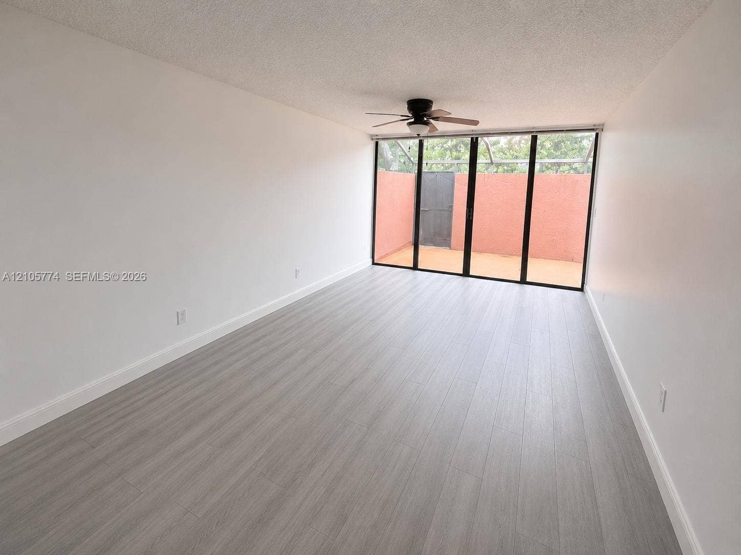 10343 Greenhouse Road, Pembroke Pines, FL 33026 Interior space featuring wood-finish flooring, floor-to-ceiling multi-panel glass doors, and a ceiling-mounted light fixture