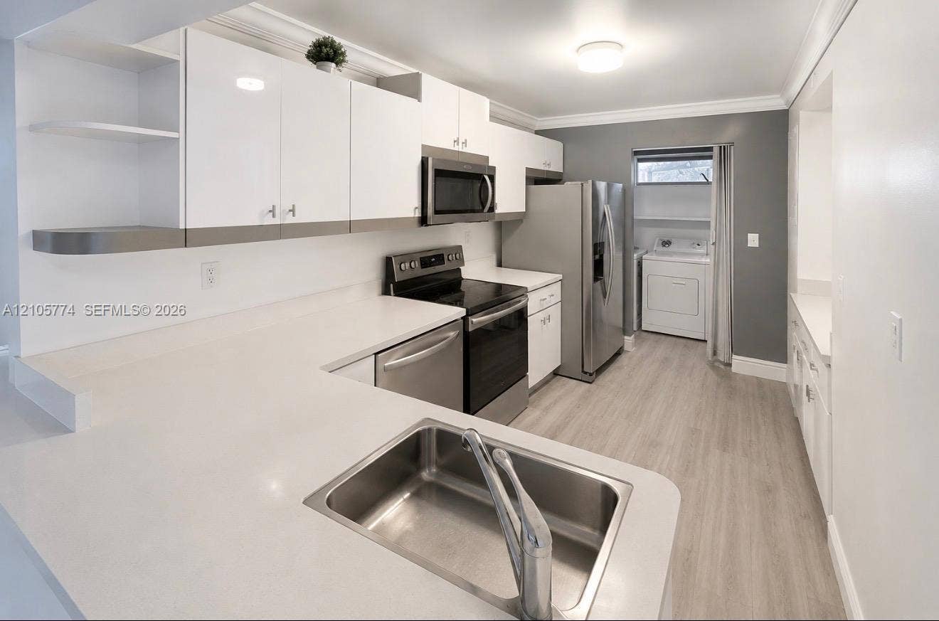 10343 Greenhouse Road, Pembroke Pines, FL 33026 Kitchen featuring white high-gloss cabinetry, solid surface countertops, stainless steel appliances, and wood-finish flooring