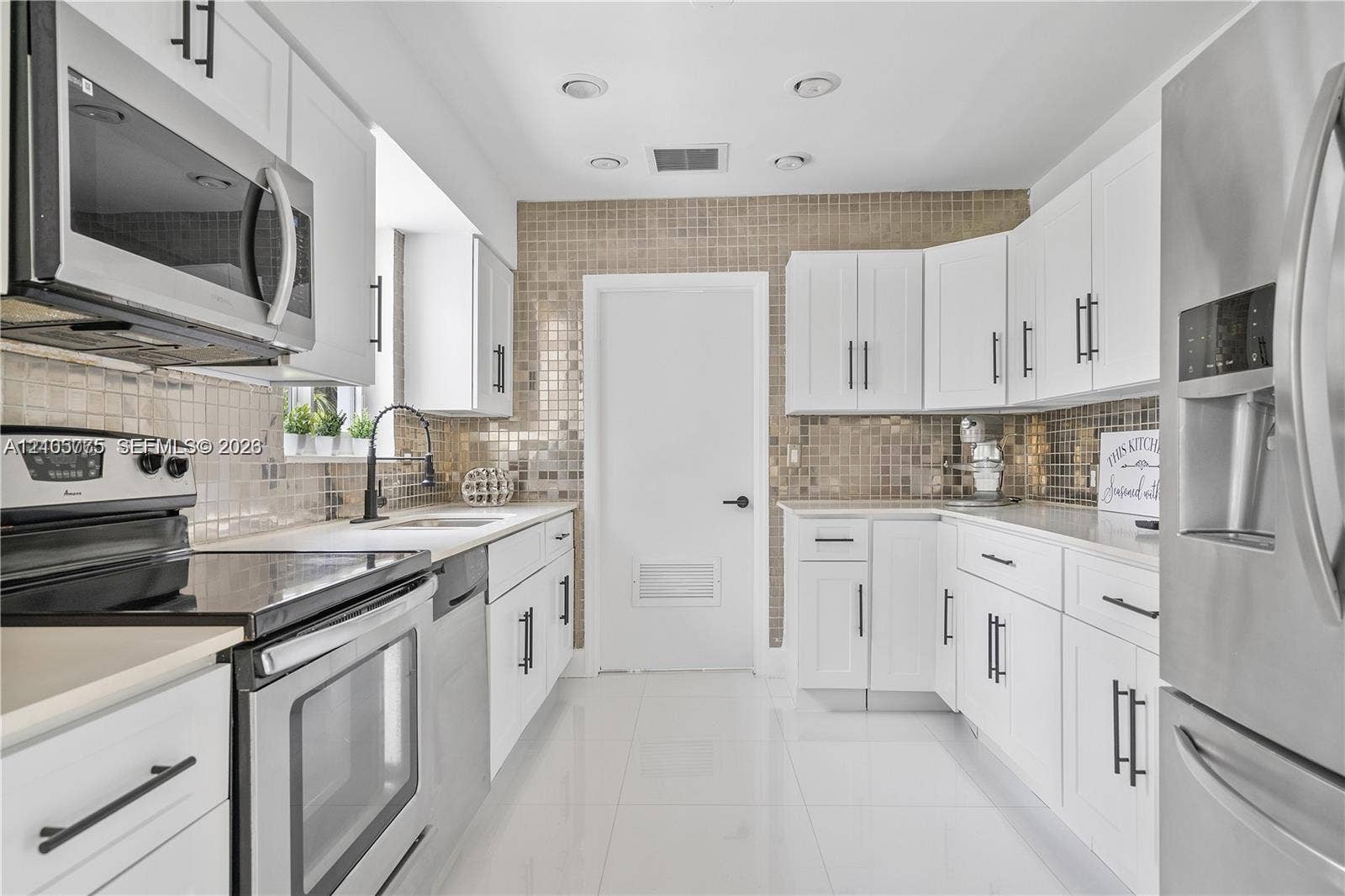 21230 NE 24th Court, Miami, FL 33180 Kitchen featuring white cabinetry with matte black hardware, stainless steel appliances, a metallic mosaic tile backsplash, and gloss-finish floor tiling