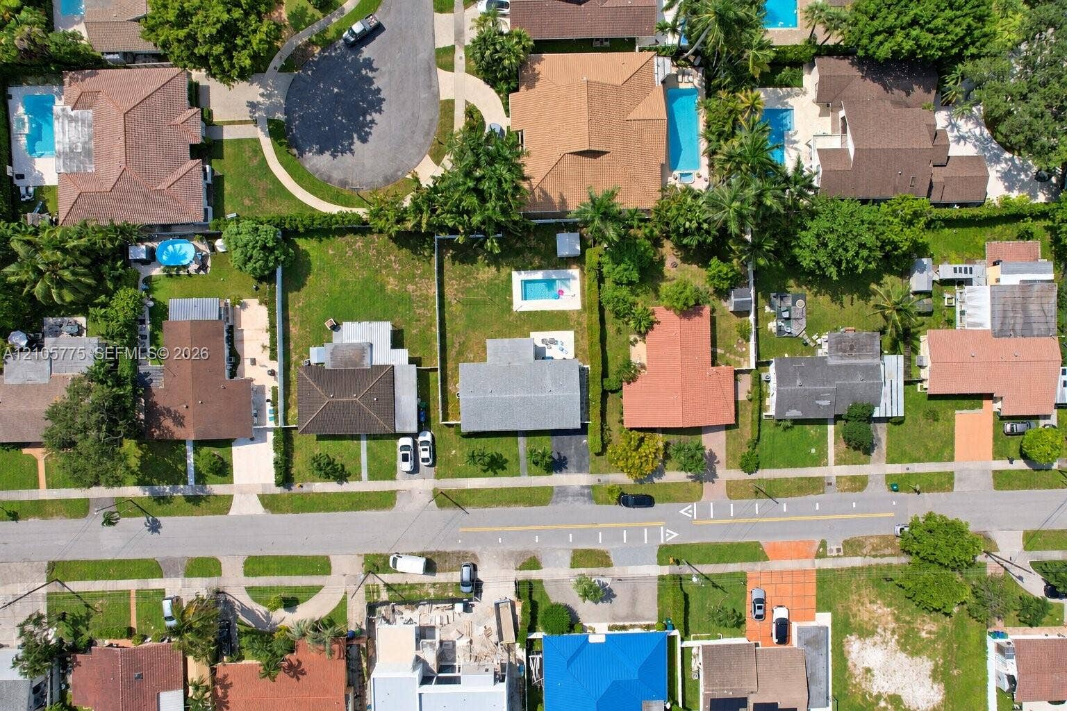 21230 NE 24th Court, Miami, FL 33180 Aerial perspective of a residential property featuring an in-ground swimming pool, fenced backyard, concrete driveway, and mature landscaping