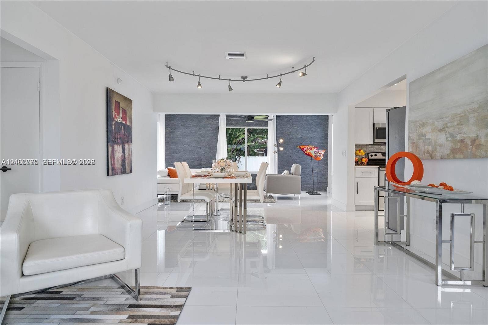 21230 NE 24th Court, Miami, FL 33180 Open-concept interior featuring polished tile flooring, recessed track lighting, and a prominent dark stone-textured accent wall