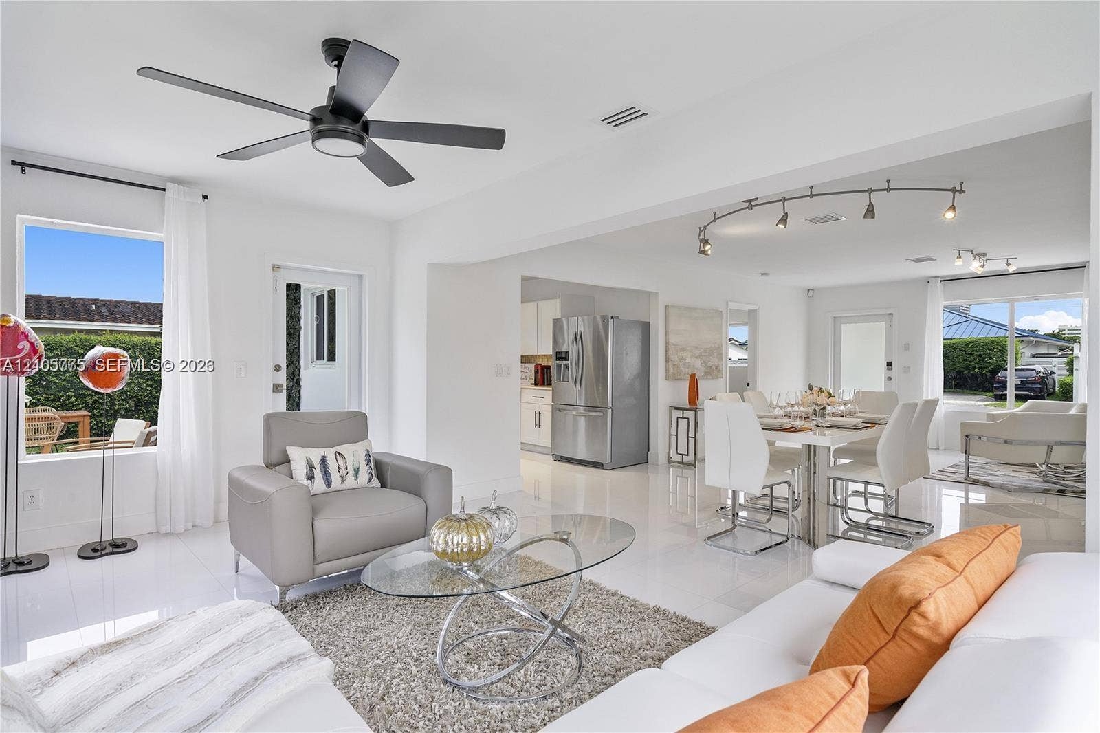 21230 NE 24th Court, Miami, FL 33180 Open-concept interior featuring polished tile flooring, matte black ceiling fan, stainless steel refrigerator, and modern track lighting