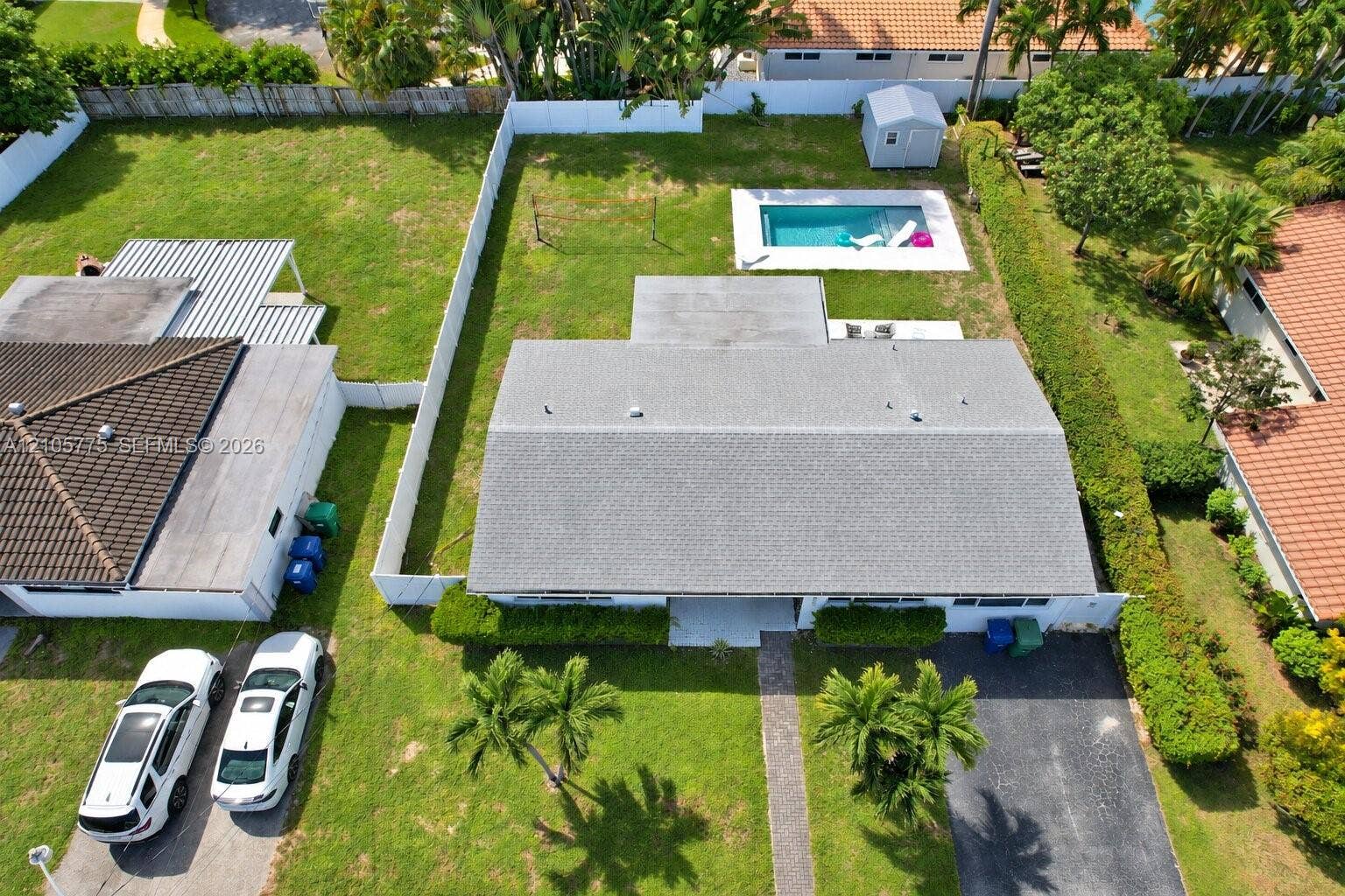 21230 NE 24th Court, Miami, FL 33180 Expansive backyard featuring an inground swimming pool, concrete patio, perimeter privacy fencing, and mature landscaping