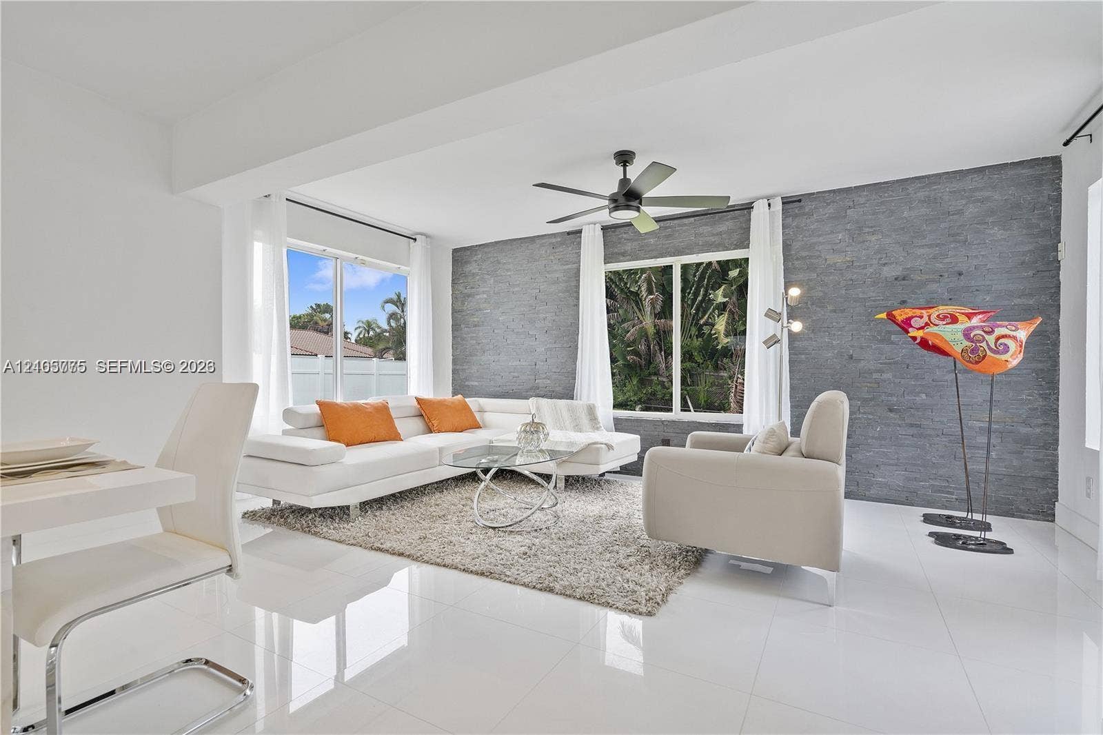 21230 NE 24th Court, Miami, FL 33180 Living area featuring large-format tile flooring, a dark stone-finish accent wall, and a central ceiling fan