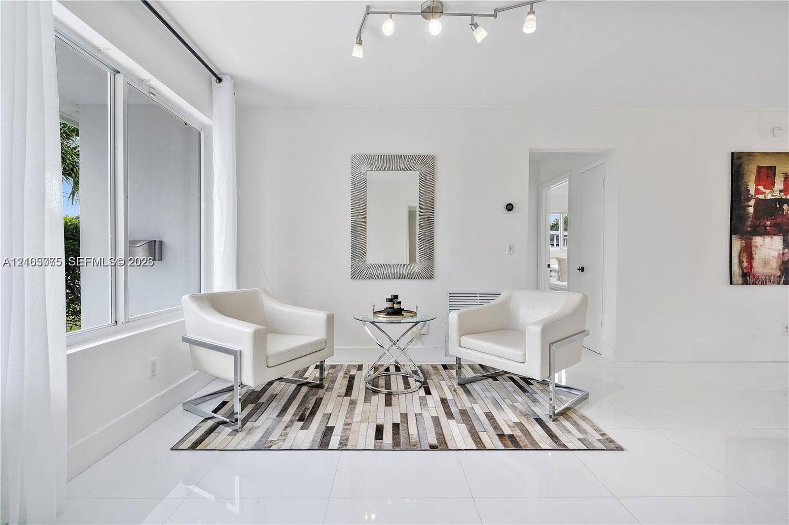 21230 NE 24th Court, Miami, FL 33180 Bright interior space featuring polished tile flooring, large multi-pane windows, and a multi-bulb track lighting fixture