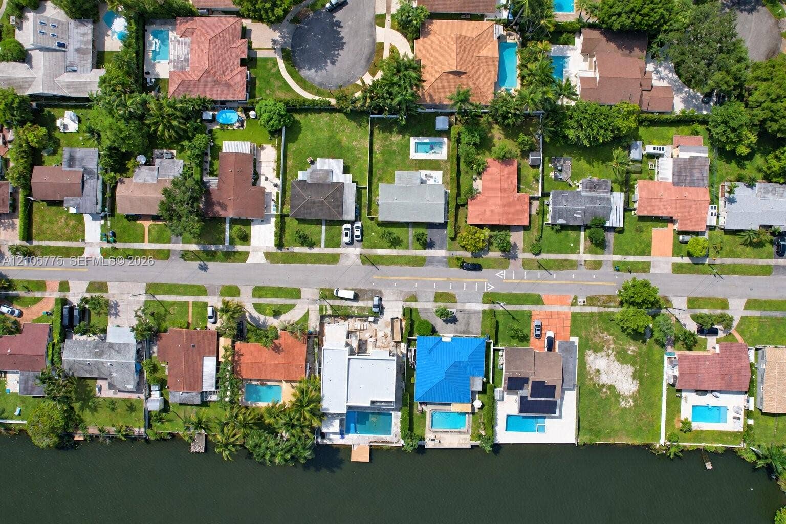 21230 NE 24th Court, Miami, FL 33180 Aerial perspective of a waterfront residential neighborhood featuring multiple properties with private swimming pools and canal access