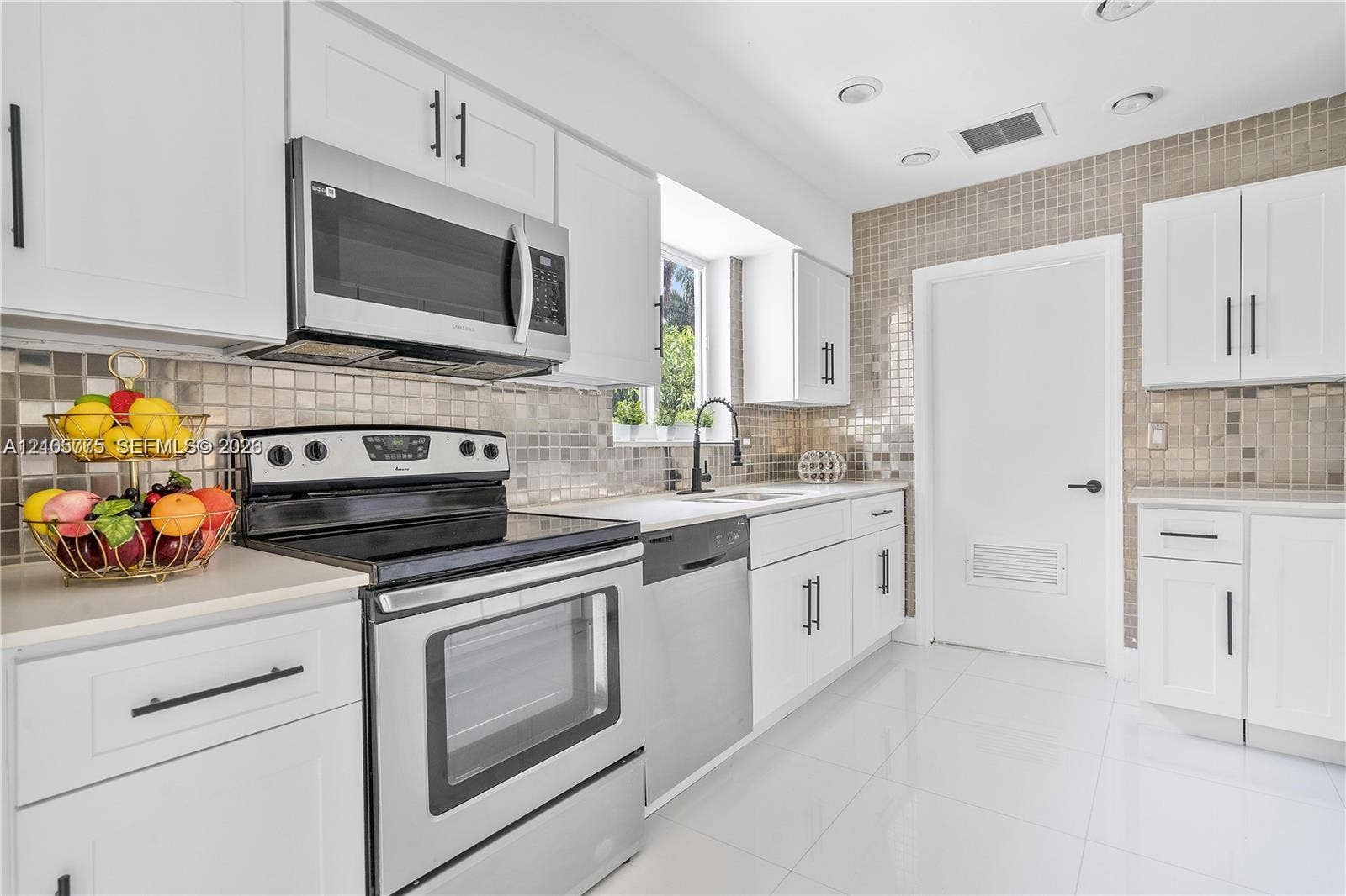 21230 NE 24th Court, Miami, FL 33180 Kitchen featuring white Shaker-style cabinetry, stainless steel appliances, a metallic mosaic tile backsplash, matte black hardware, and tile flooring