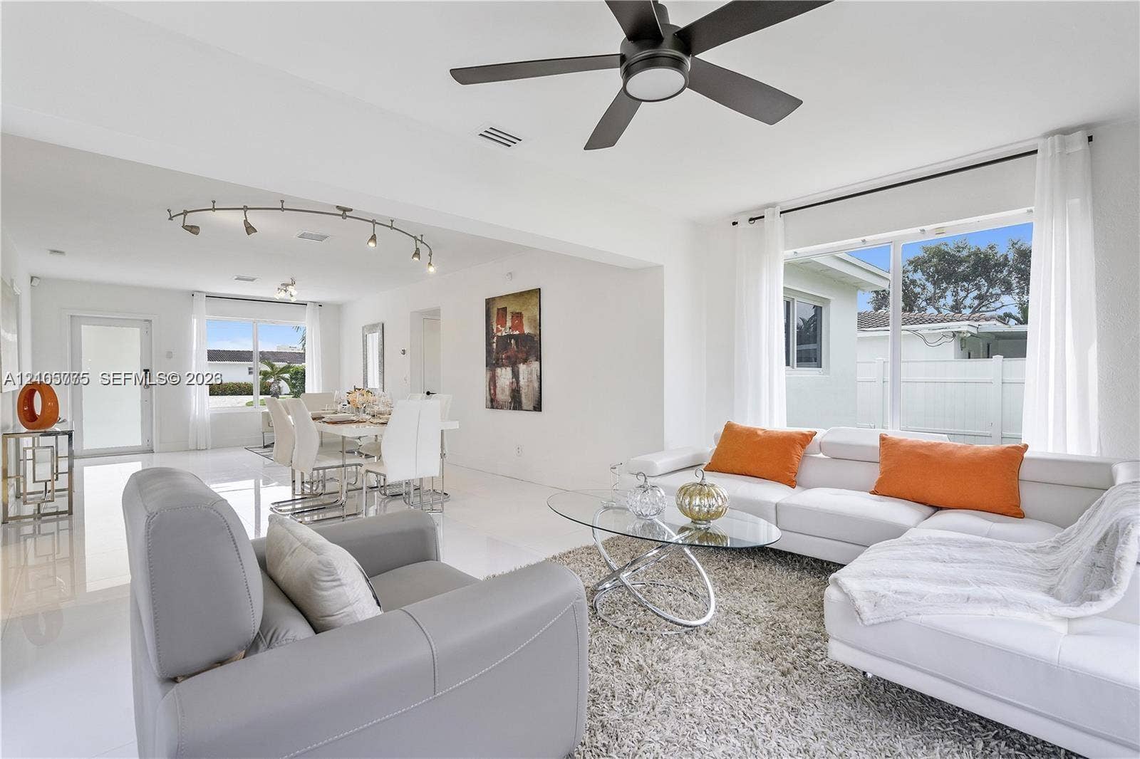 21230 NE 24th Court, Miami, FL 33180 Open-concept interior featuring large-format tile flooring, matte black ceiling fan, and adjustable track lighting