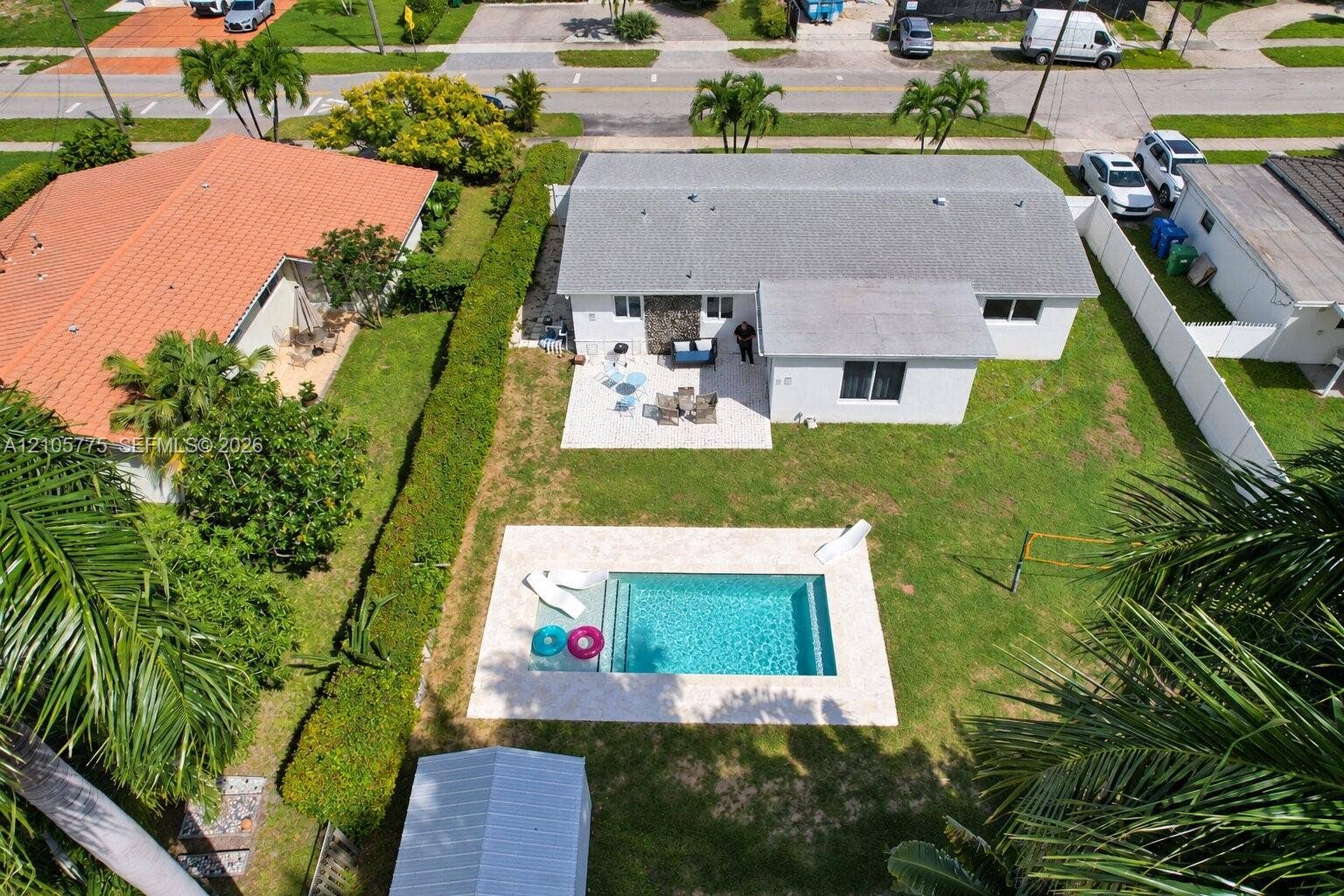 21230 NE 24th Court, Miami, FL 33180 Fenced backyard featuring an in-ground swimming pool, stone-finish pool deck, concrete patio, and stone exterior accent