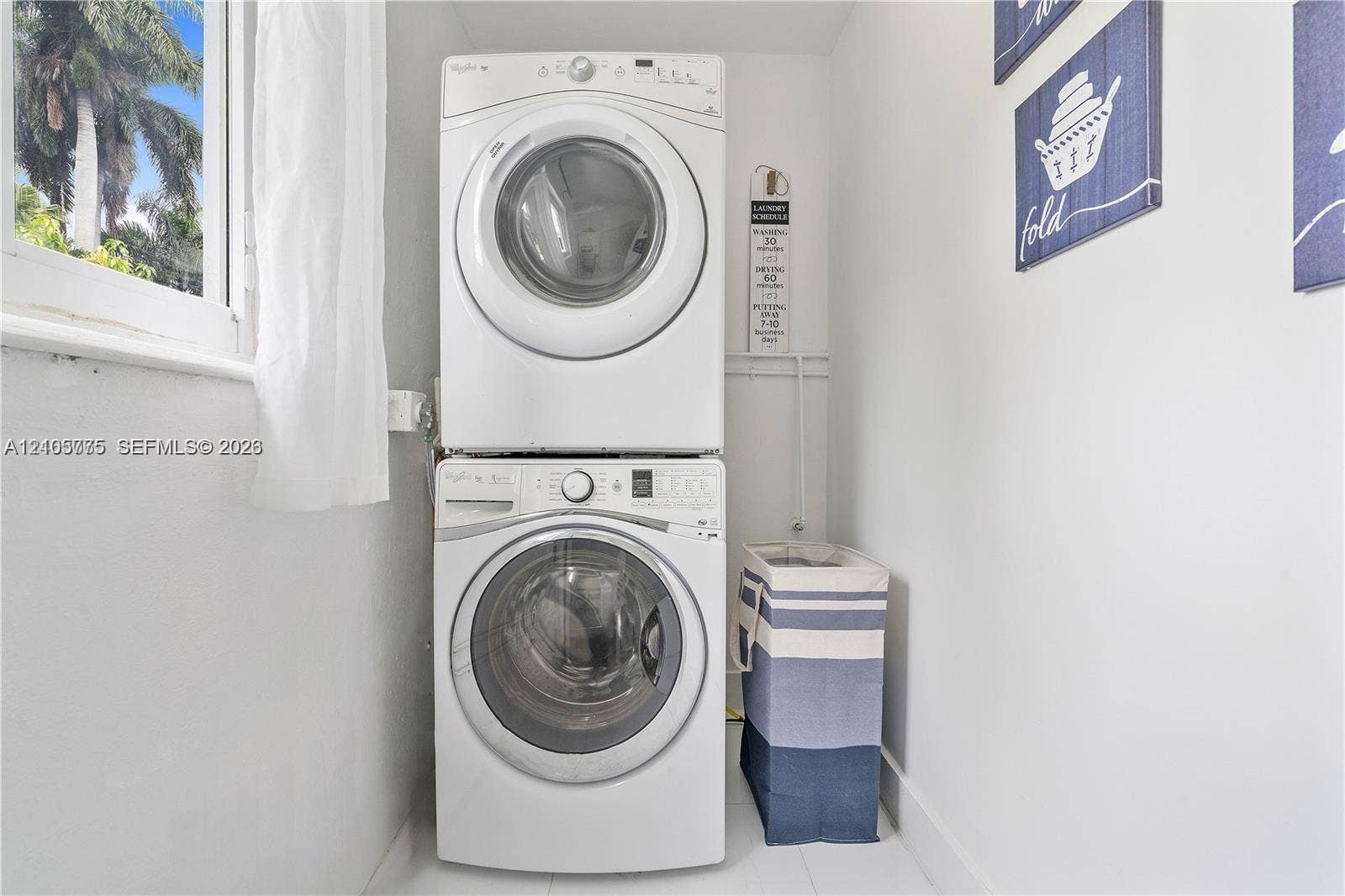 21230 NE 24th Court, Miami, FL 33180 Dedicated laundry area featuring a white stackable front-load washer and dryer set and a window providing natural light