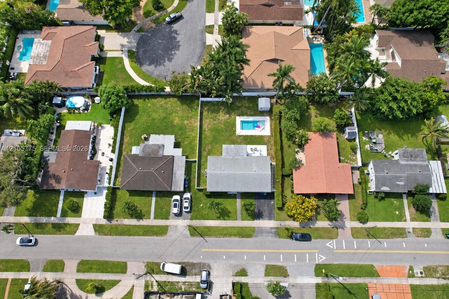 21230 NE 24th Court, Miami, FL 33180 Aerial perspective of a residential property featuring an in-ground swimming pool, a fenced backyard, and a paved driveway