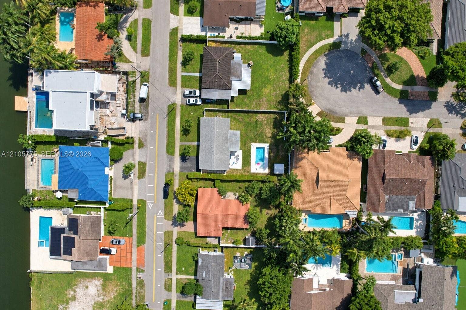 21230 NE 24th Court, Miami, FL 33180 Aerial view of a waterfront residential neighborhood featuring in-ground swimming pools, mature palm trees, and canal access