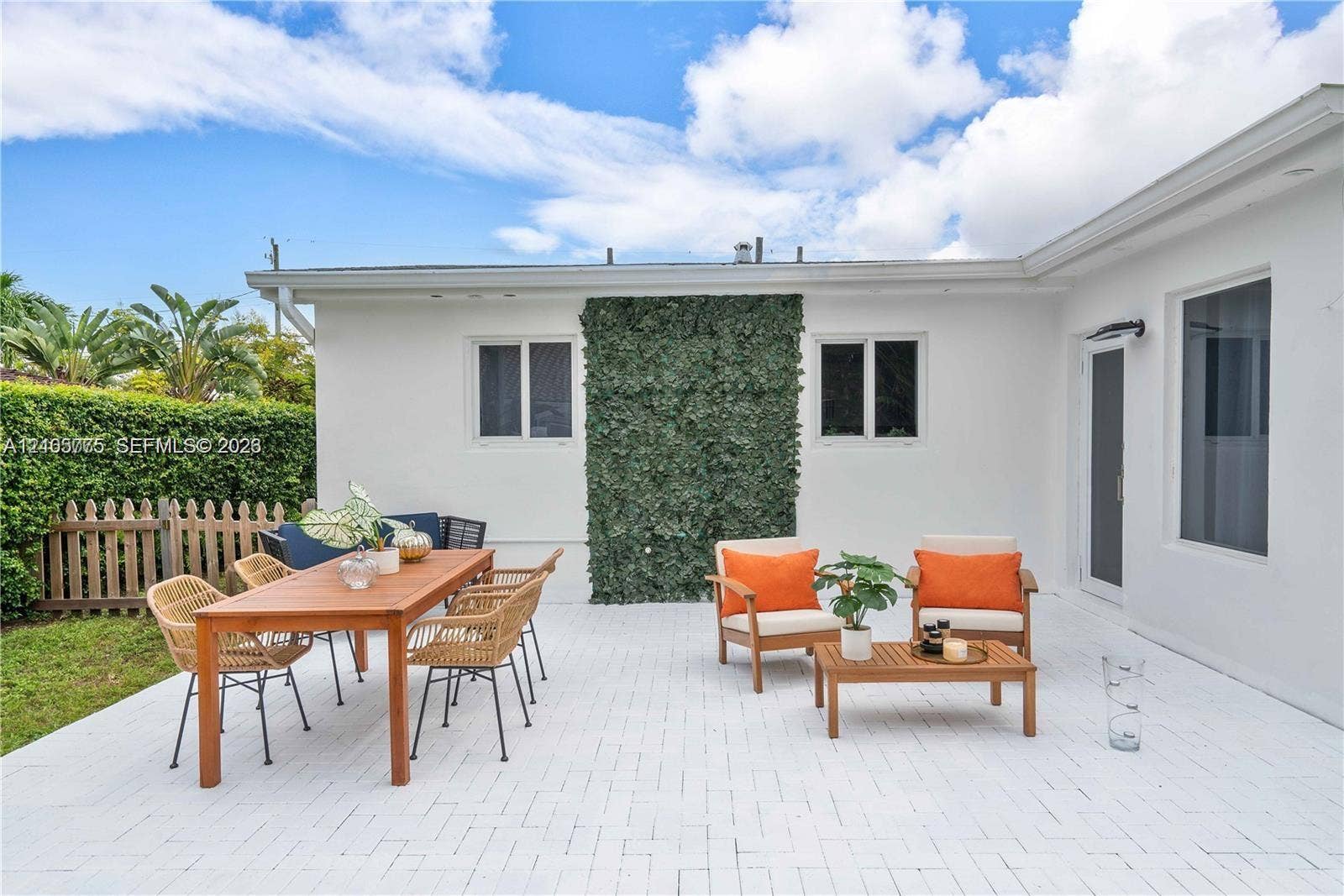 21230 NE 24th Court, Miami, FL 33180 Outdoor patio featuring white brick pavers, a vertical exterior green wall, and a wood picket fence enclosure