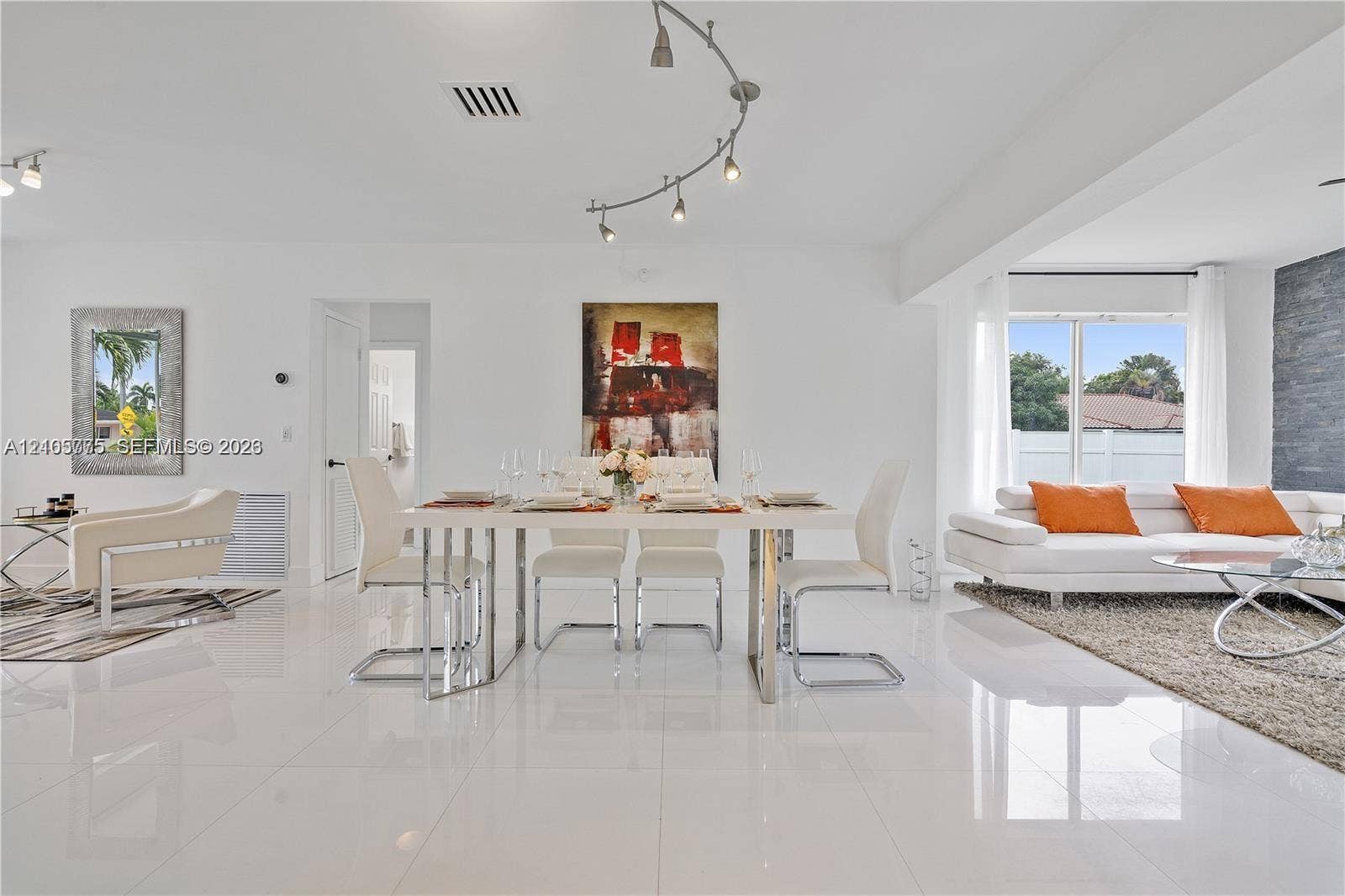 21230 NE 24th Court, Miami, FL 33180 Open-concept living space featuring high-gloss tile flooring, adjustable track lighting, and a prominent gray stone-textured accent wall