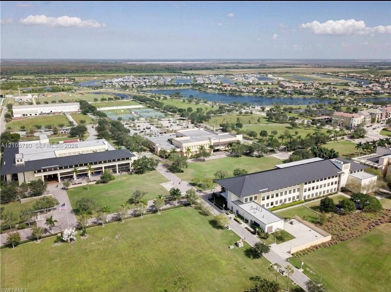 Aerial perspective featuring multi-story commercial buildings, expansive manicured lawns, paved pedestrian pathways, and surrounding water features