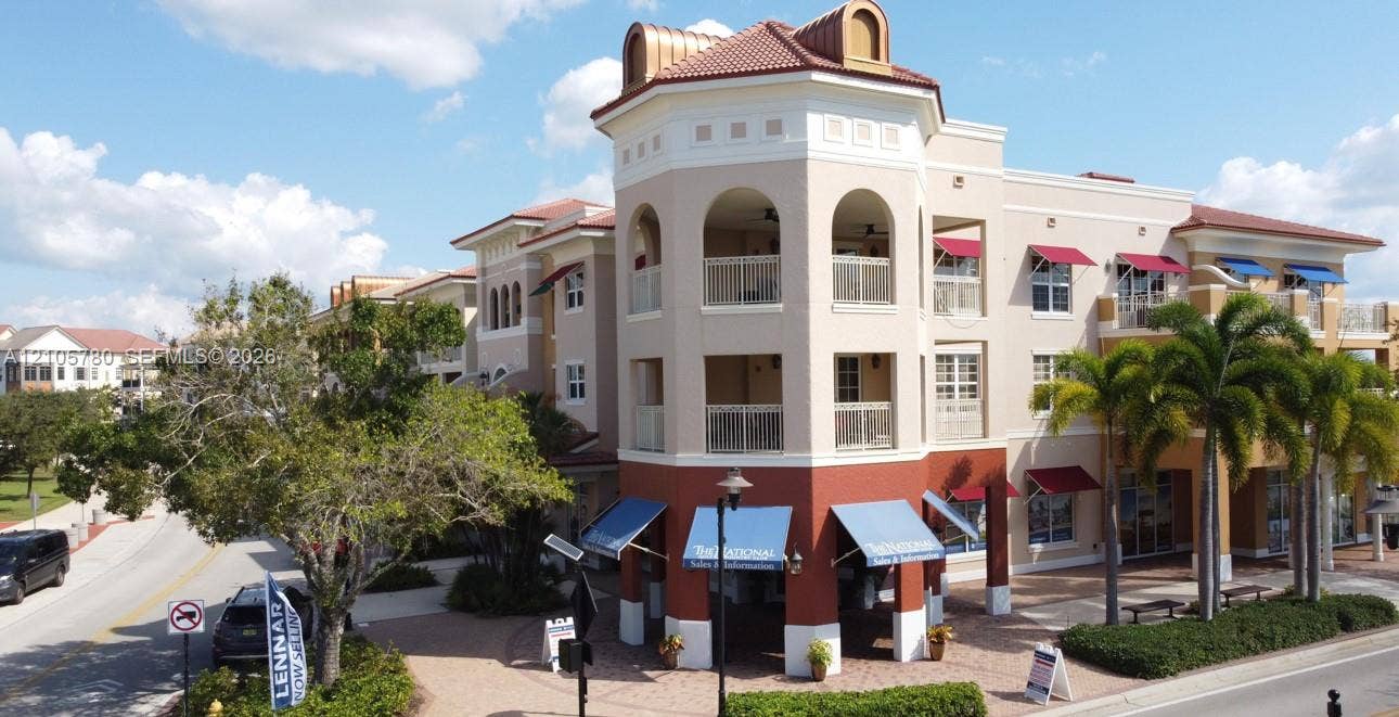 Multi-story exterior featuring arched upper-level balconies, stucco facade, decorative copper-toned roof accents, and integrated retractable fabric awnings