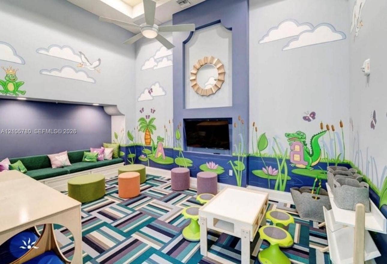 High-ceilinged room featuring built-in bench seating, custom wall murals, a central recessed architectural niche, and a ceiling-mounted light fixture