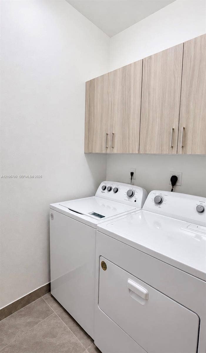 Utility space featuring custom wood-finish upper cabinetry, brushed nickel hardware, and neutral-tone tile flooring
