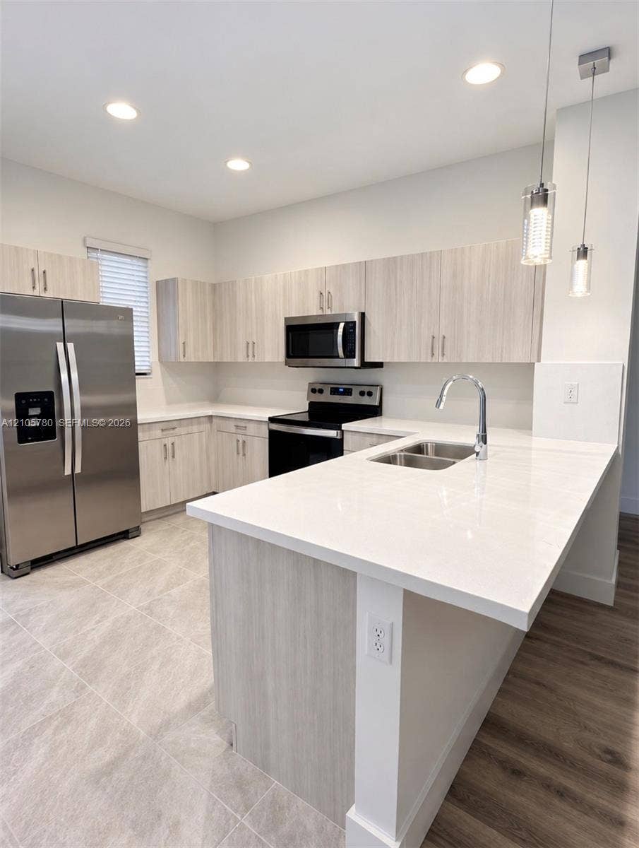 Kitchen featuring light-toned cabinetry, quartz countertops, stainless steel appliances, a double-basin undermount sink, and recessed lighting