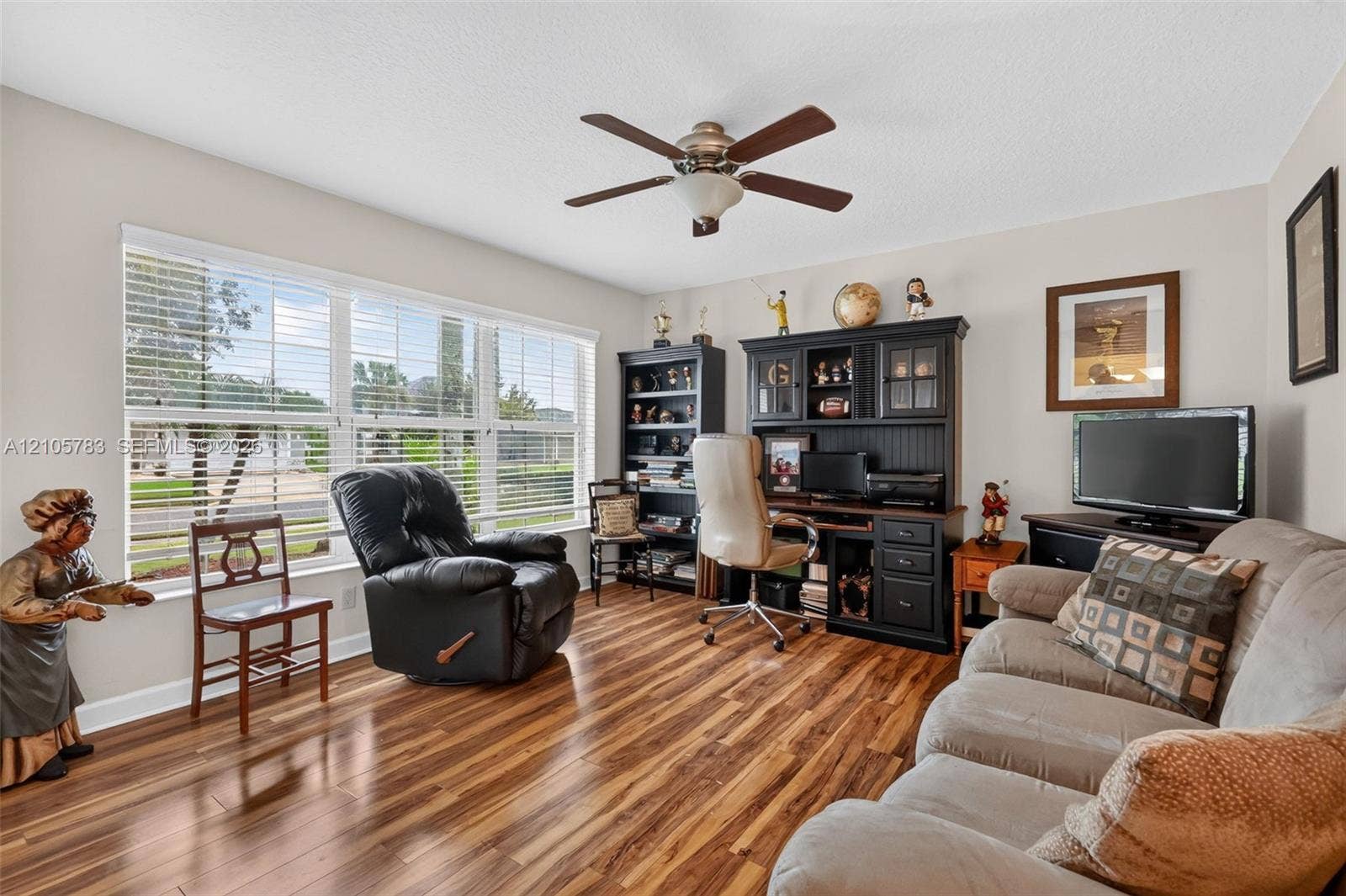 Room featuring wood-finish flooring, large multi-pane windows, and a ceiling fan with integrated lighting