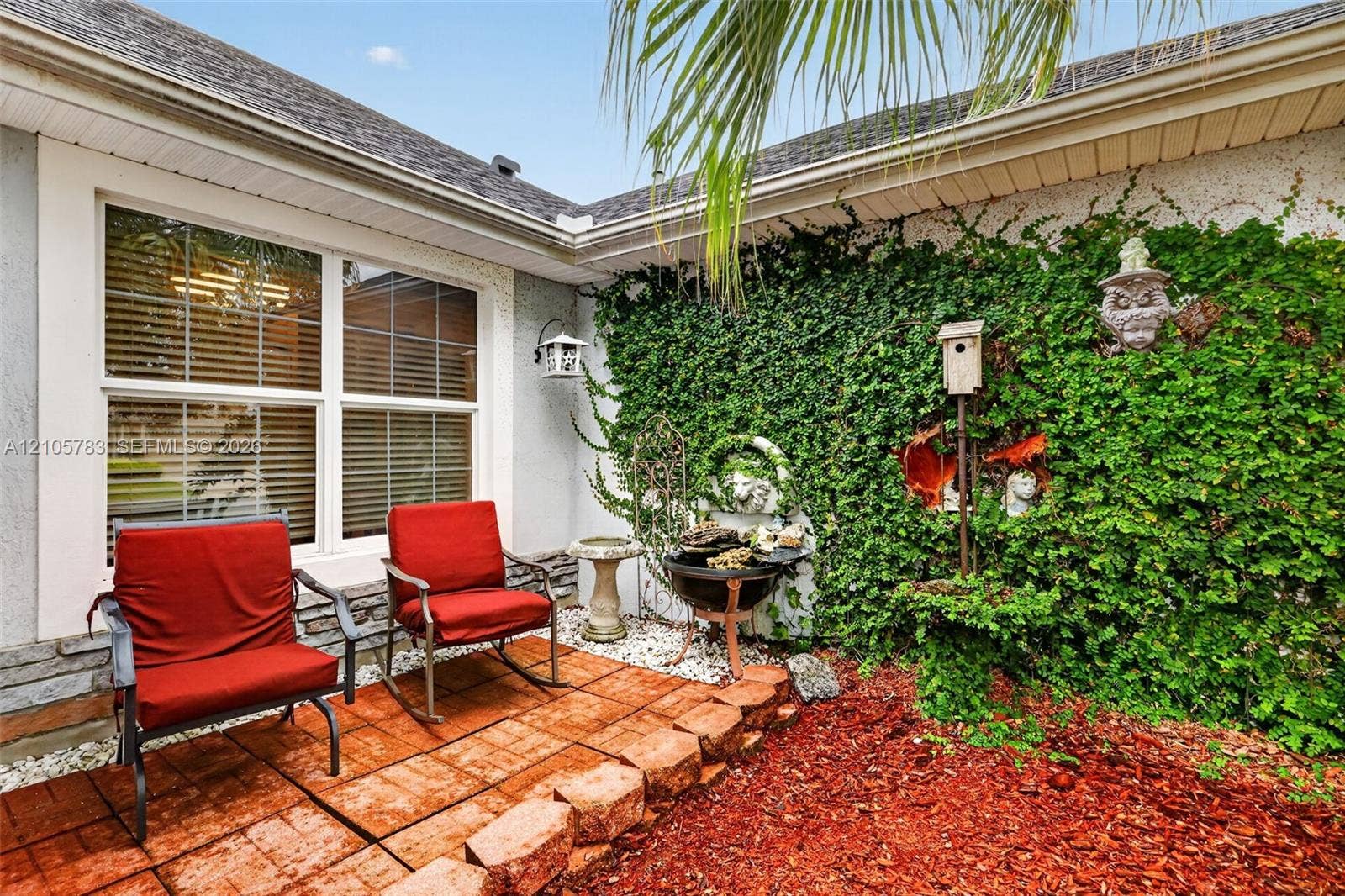 Private courtyard featuring a terra-cotta tile patio, stone-veneer siding, and a climbing ivy wall