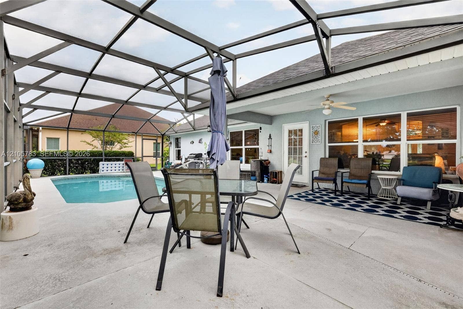 Screen-enclosed patio featuring a concrete deck, swimming pool, and ceiling-mounted fan