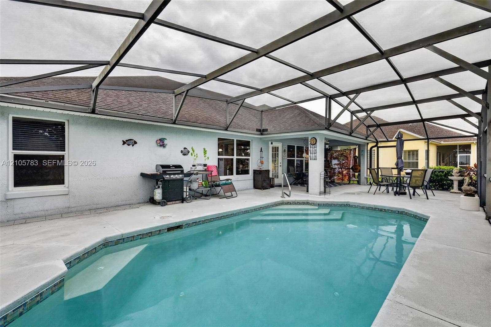 Screened-in outdoor living area featuring a swimming pool with integrated stairs and a concrete patio deck