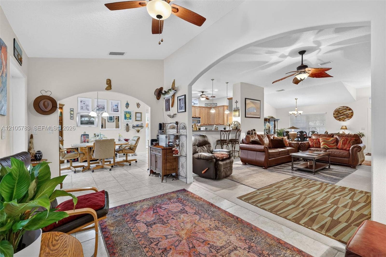 Open-concept interior featuring vaulted ceilings, arched architectural entries, tile flooring, and multiple ceiling fans