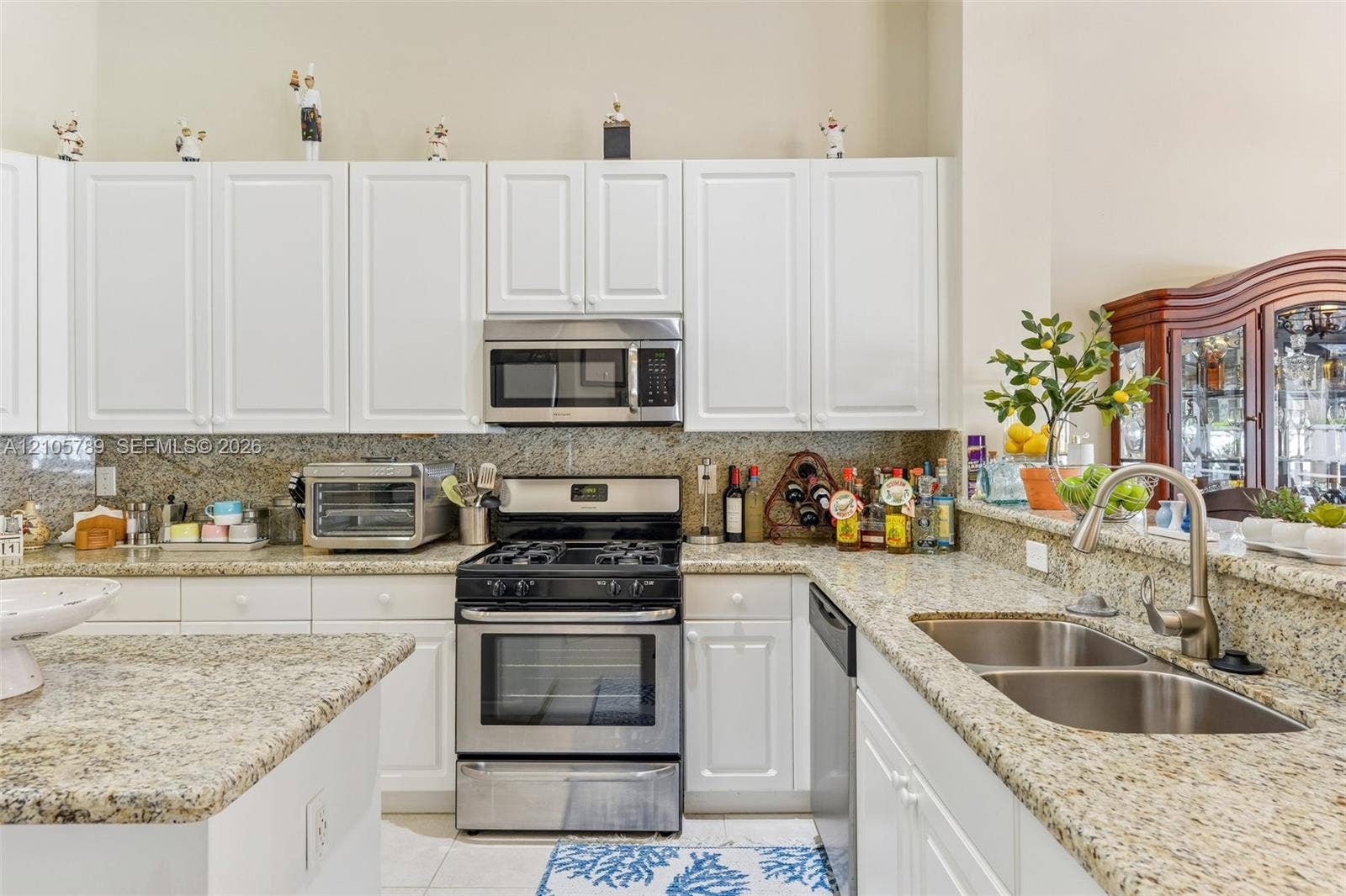 6353 SW 191st Avenue, Pembroke Pines, FL 33332 Kitchen featuring white shaker-style cabinetry, stone countertops, stainless steel appliances, and a dual-basin undermount sink with a gooseneck faucet