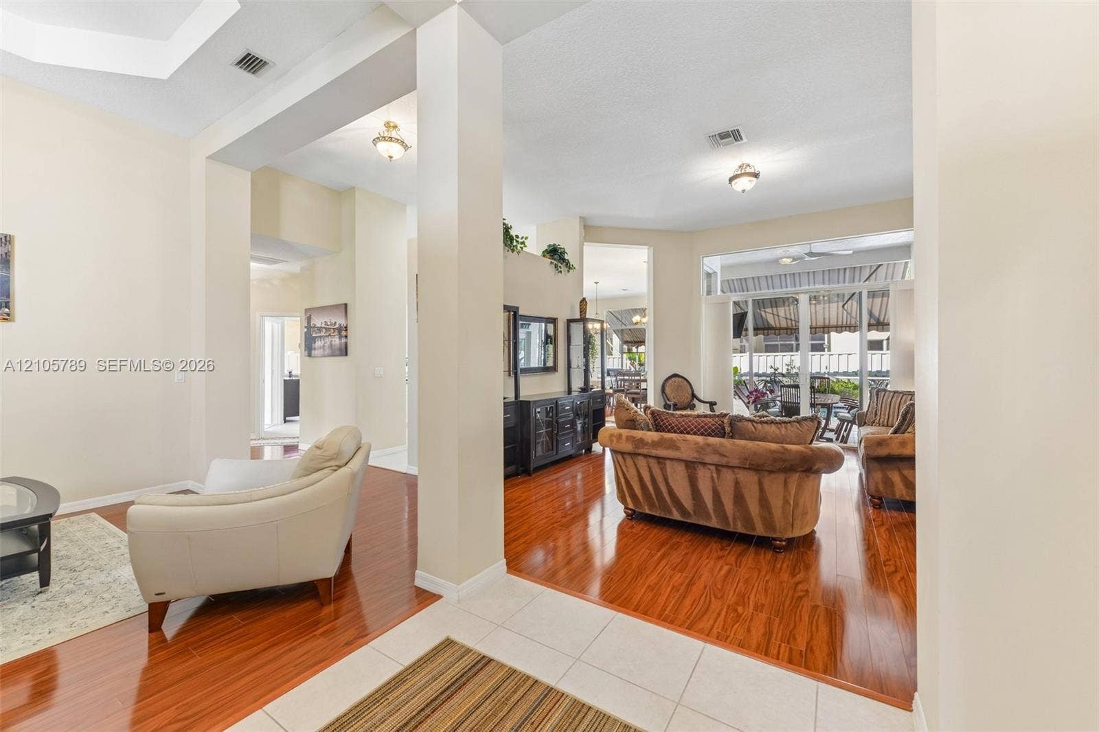 6353 SW 191st Avenue, Pembroke Pines, FL 33332 Open-concept interior featuring tray ceilings, wood-finish flooring, recessed lighting, and large sliding glass doors