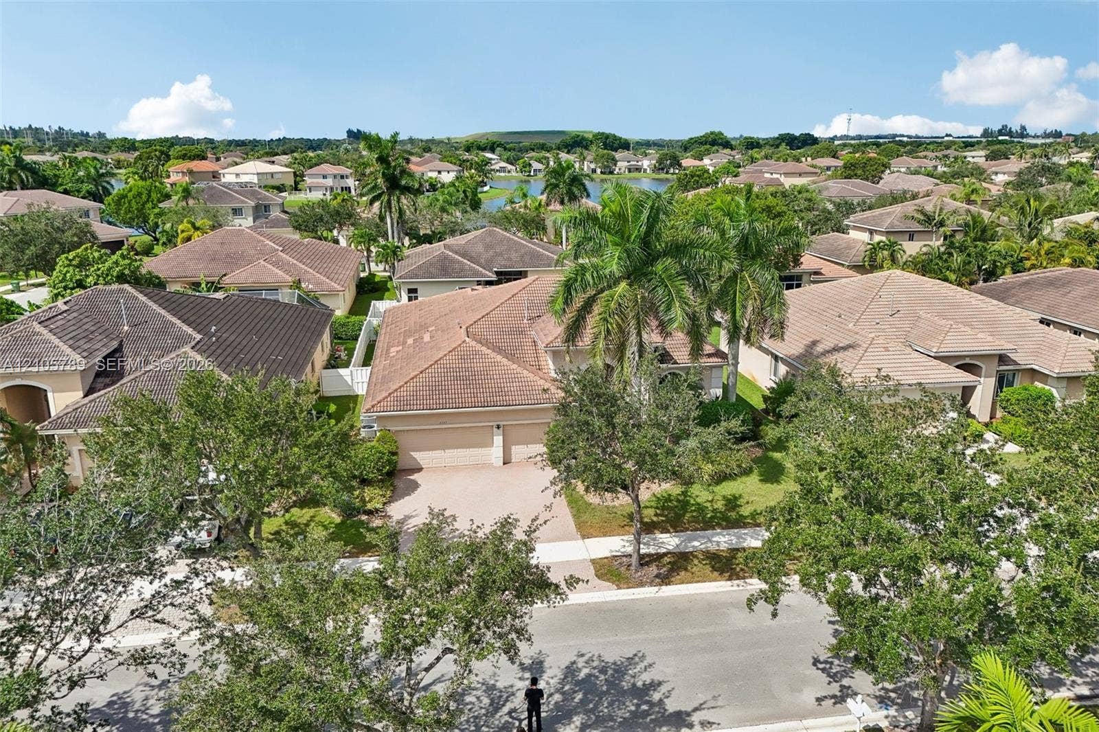 6353 SW 191st Avenue, Pembroke Pines, FL 33332 Aerial perspective of a multi-hip roof residential property featuring a paved driveway, a two-car garage, established palm trees, and mature landscaping