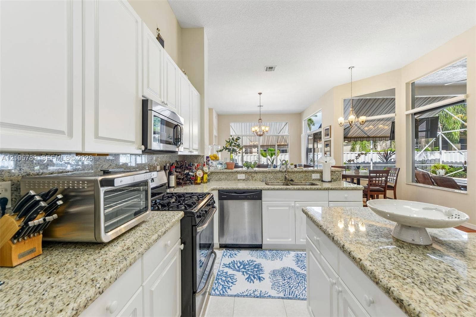 6353 SW 191st Avenue, Pembroke Pines, FL 33332 Kitchen featuring white cabinetry, stone countertops, stainless steel appliances, a center island, and expansive windows